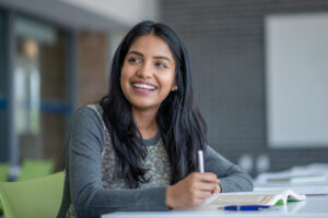 female higher ed student smiling at desk