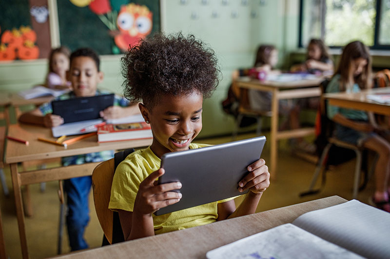 Young girl sitting in a classroom reading a tablet
