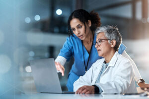 two female doctors looking at laptop screen together