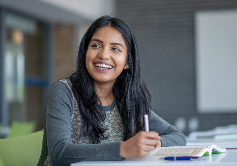 female higher ed student smiling at desk