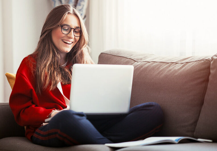 woman-laptop-couch-800x533 woman seated on couch smiling at laptop